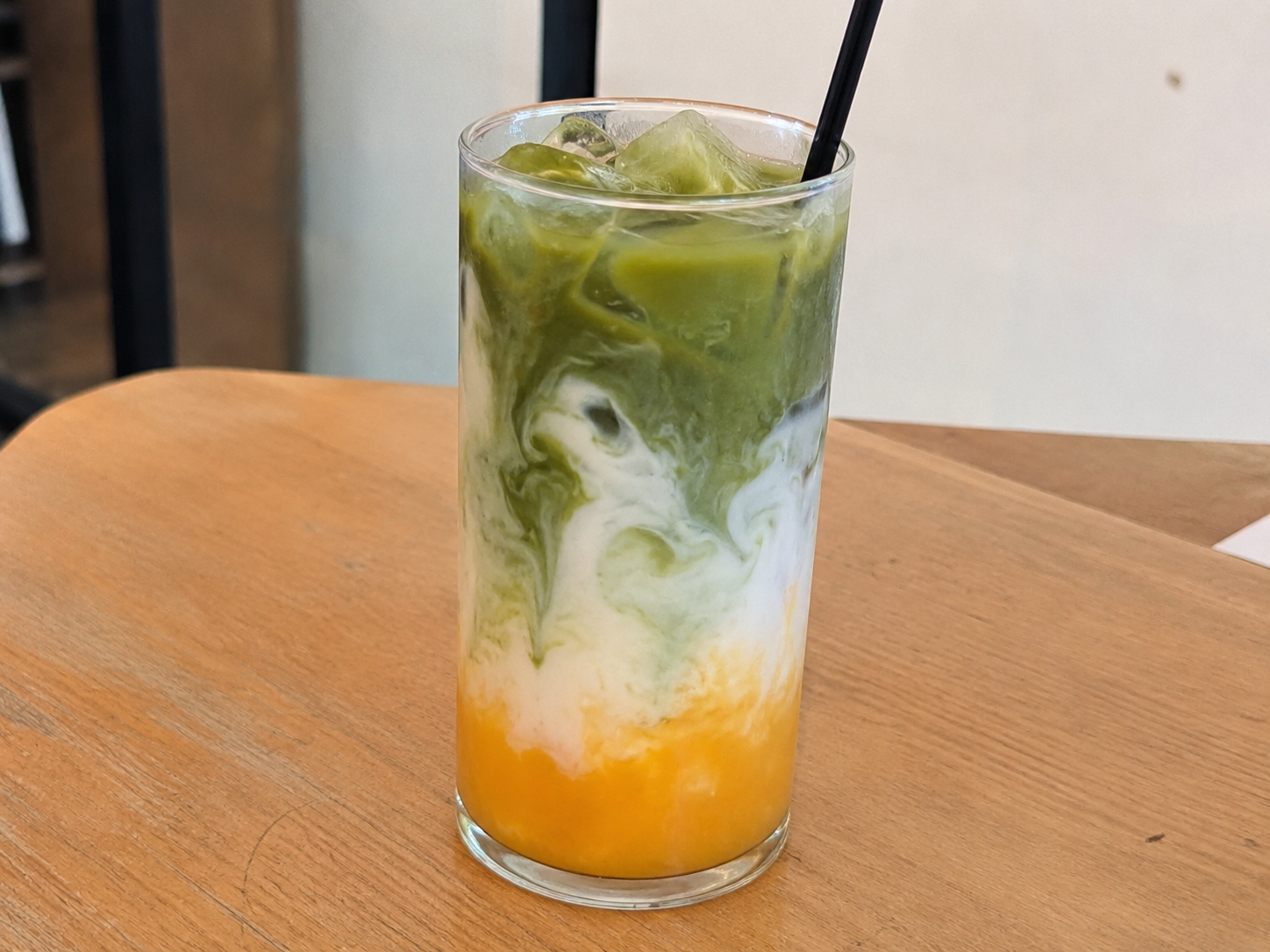 Reference photo: a glass of layered mango matcha drink on a table