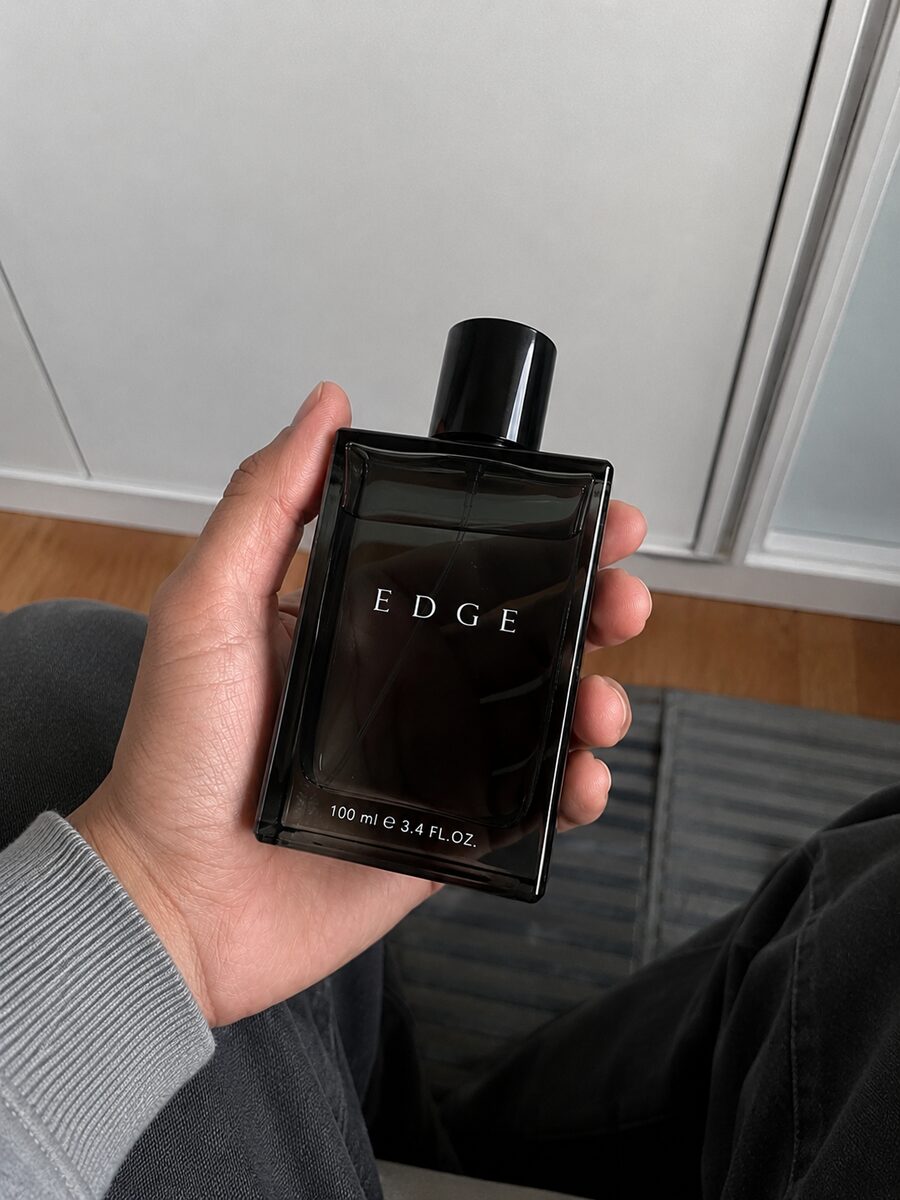 Reference photo: a hand holding the black EDGE fragrance bottle